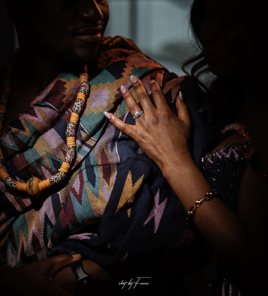Ghanaian bride rests hand on groom's shoulder while showing off wedding ring