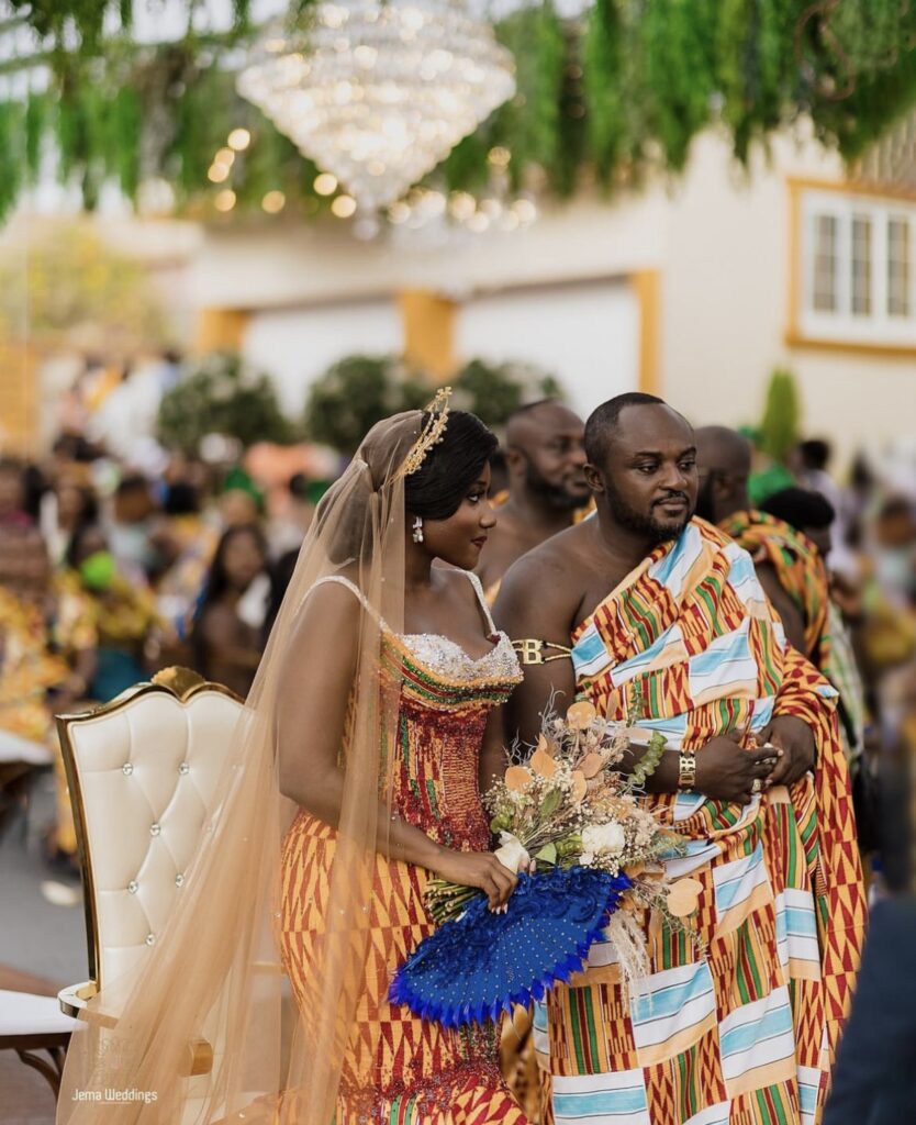 Ghanaian bride and Ghanaian groom standing in Kente wedding dress during their ceremony