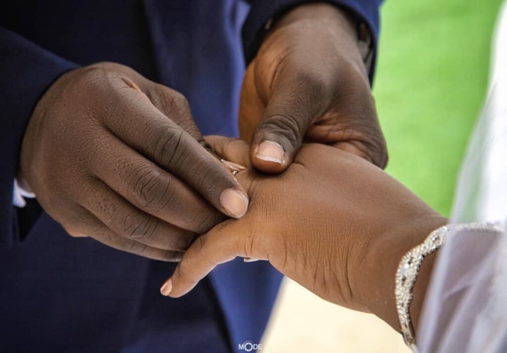 Ghanaian groom putting a ring on the finger of Ghanaian bride during wedding ceremony 